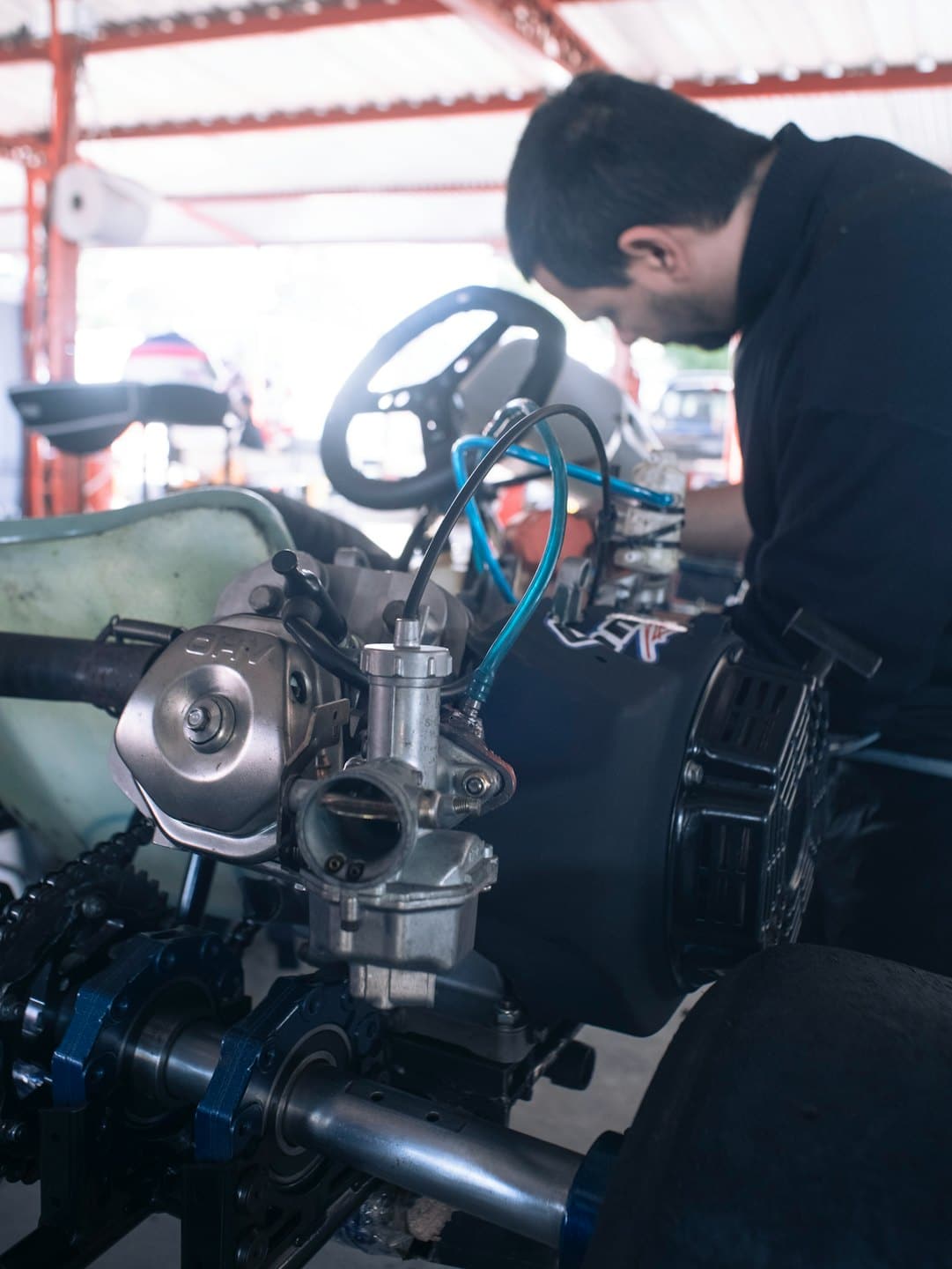 Tamirhanede go-kart motoru üzerinde çalışan tamirci.